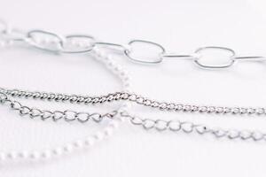 A necklace of white beads with chains of jewelry on a white aesthetic background. photo