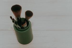 Green case with make-up bones on a wooden table. photo