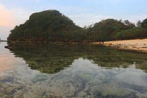 Malang's Tri-Color Coastal Vista, where azure waves meet golden sands under a vibrant sky photo