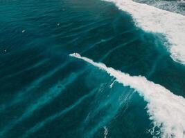 Aerial view with surfing on wave in tropics. Perfect waves with surfers in transparent ocean photo