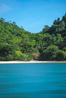 Aerial panorama of Thailand's verdant, lush tropical island, National Park Island, with blue and aquamarine the sea, and clouds shining by sunlight in the background. photo