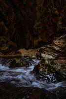 The beautiful views of the stalactite and stalagmite-filled cave in Lam Khlong Ngu National Park, Thailand. At the cave's exit is a small waterfall also. photo