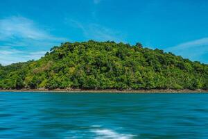 Aerial panorama of Thailand's verdant, lush tropical island, National Park Island, with blue and aquamarine the sea, and clouds shining by sunlight in the background. photo