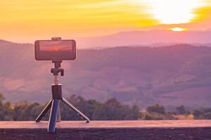 A smartphone is recording the sun setting over a mountain range. photo