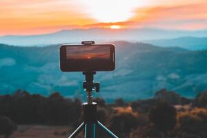 A smartphone is recording the sun setting over a mountain range. photo