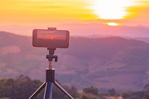 A smartphone is recording the sun setting over a mountain range. photo