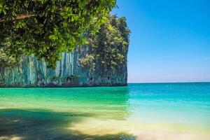 Aerial panorama of Thailand's verdant, lush tropical island, National Park Island, with blue and aquamarine the sea, and clouds shining by sunlight in the background. photo