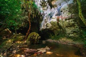 The beautiful views of the stalactite and stalagmite-filled cave in Lam Khlong Ngu National Park, Thailand. At the cave's exit is a small waterfall also. photo