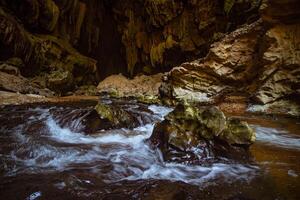 The beautiful views of the stalactite and stalagmite-filled cave in Lam Khlong Ngu National Park, Thailand. At the cave's exit is a small waterfall also. photo