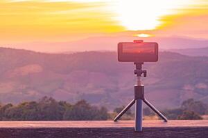 A smartphone is recording the sun setting over a mountain range. photo