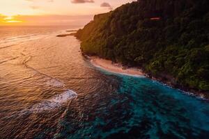 Beautiful coastline with beach and bright warm sunset in Bali. Aerial view photo