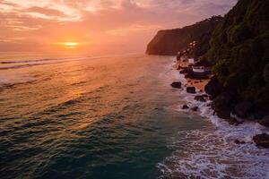 Coastline beach with bright sunset or sunrise tones in Bali. Popular destination beach. Aerial view photo