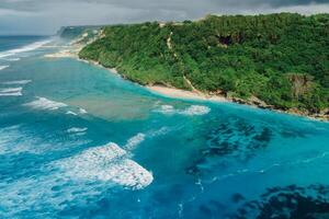 Beach coastline with turquoise ocean and waves in Bali. Aerial view photo