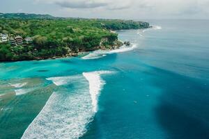 Blue ocean with perfect waves and coastline on Padang Padang surf spot in Bali. Aerial view photo