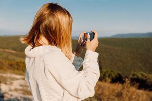 Blonde woman photography with smartphone. Girl shooting landscapes on smartphone photo