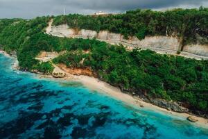 Beach under cliffs with turquoise ocean in Bali. Aerial view photo