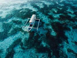 Boat at anchor in transparent ocean on tropical island. Aerial view. photo