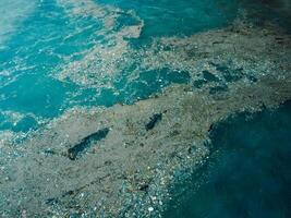 Ocean water and plastic trash in Bali. Aerial view of pollution by plastic rubbish photo