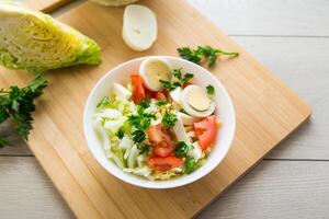 Fresco vegetal ensalada, repollo, Tomates en un cuenco en un de madera mesa foto