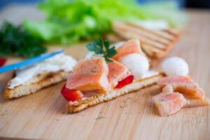 fried toast with salmon, cream cheese, salad, on a wooden table photo