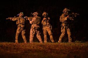 soldados en camuflaje uniformes puntería con su rifles Listo a fuego durante militar operación a noche, soldados formación en un militar operación foto