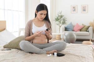 Pregnant woman checking blood sugar level by using Digital Glucose meter, health care, medicine, diabetes, glycemia concept photo