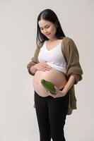 retrato de hermosa embarazada mujer participación aguacate terminado blanco antecedentes estudio, salud y maternidad concepto foto