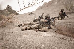 soldados en camuflaje uniformes puntería con su rifles Listo a fuego durante militar operación en el Desierto soldados formación en un militar operación foto