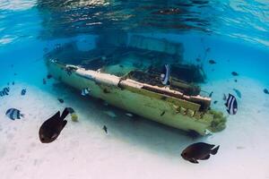 Tropical ocean with wreck of boat on sandy bottom and school of fish, underwater in Mauritius photo