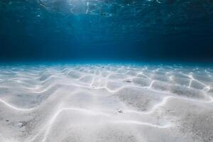 Tropical blue ocean with white sand underwater and waves photo