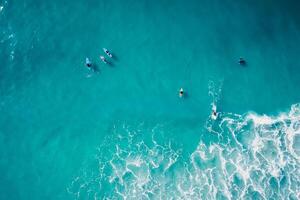 surfistas remo en tablas de surf en transparente turquesa Oceano esperando ola. aéreo ver foto