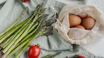 Fresco espárragos y marrón huevos en un ligero antecedentes con Cereza Tomates video