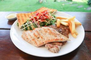 Cerdo filete y pollo filete con francés papas fritas ,pan y ensalada o A la parrilla Cerdo y A la parrilla pollo foto