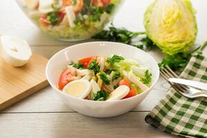 Fresco vegetal ensalada, repollo, Tomates en un cuenco en un de madera mesa foto