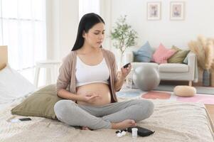 Pregnant woman checking blood sugar level by using Digital Glucose meter, health care, medicine, diabetes, glycemia concept photo