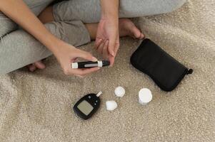 Close up of woman checking blood sugar level by using Digital Glucose meter, health care, medicine, diabetes, glycemia concept photo