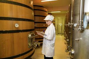 Professional winemaker controlling wine making process and quality at winery factory photo
