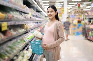 hermosa embarazada mujer compras sano comida a tienda de comestibles tienda foto