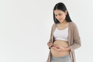 Pregnant woman checking blood sugar level by using Digital Glucose meter, health care, medicine, diabetes, glycemia concept photo