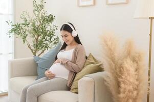 contento embarazada mujer con auriculares escuchando a mozart música y acostado en sofá, el embarazo concepto foto