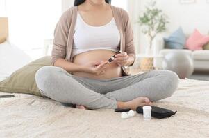 Pregnant woman checking blood sugar level by using Digital Glucose meter, health care, medicine, diabetes, glycemia concept photo