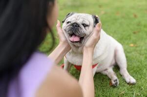 contento asiático mujer jugando con linda inteligente doguillo perrito perro en el patio interior foto