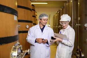 Professional winemaker controlling wine making process and quality at winery factory photo