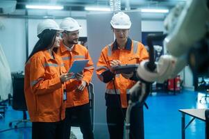 un grupo de robótica ingenieros trabajando con programación y manipulando robot mano, industrial robótica diseño, alto tecnología instalación, moderno máquina aprendiendo. masa producción automáticas. foto