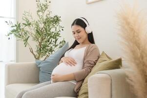contento embarazada mujer con auriculares escuchando a mozart música y acostado en sofá, el embarazo concepto foto
