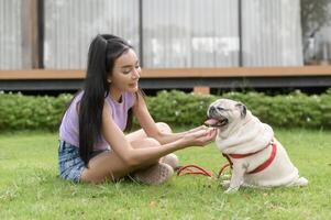 contento asiático mujer jugando con linda inteligente doguillo perrito perro en el patio interior foto