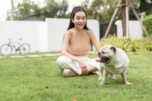 Happy asian woman playing with Cute Smart pug Puppy Dog In the Backyard photo