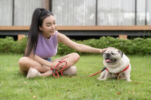 contento asiático mujer jugando con linda inteligente doguillo perrito perro en el patio interior foto