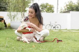 contento asiático mujer jugando con linda inteligente doguillo perrito perro en el patio interior foto