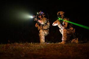 soldados en camuflaje uniformes puntería con su rifles Listo a fuego durante militar operación a noche soldados formación en un militar operación foto